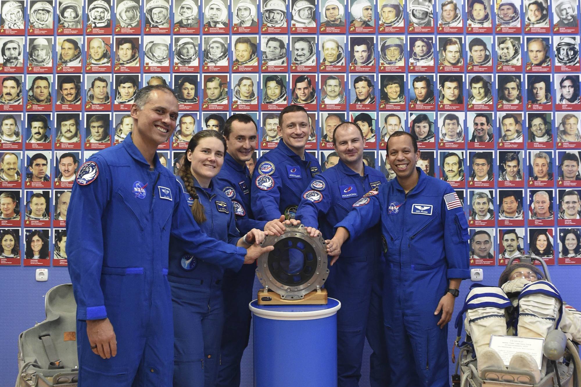 Les équipages posent devant une pièce du périscope Vizor. En arrière-plan les photos de tous les cosmonautes soviétiques et russes.