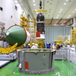 Les différents "morceaux" du composite supérieur sur la même image: Compartiment de transfert (au centre), coiffe (à gauche) et cargo en arrière-plan.