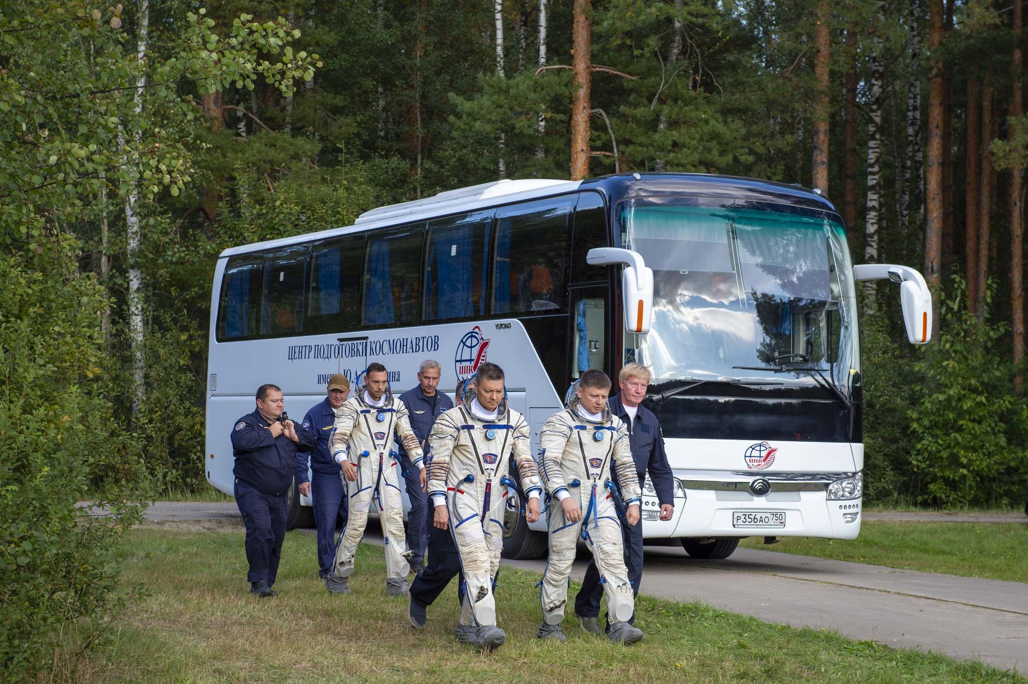 Les cosmonautes en combinaison spatiale arrivent en bus.